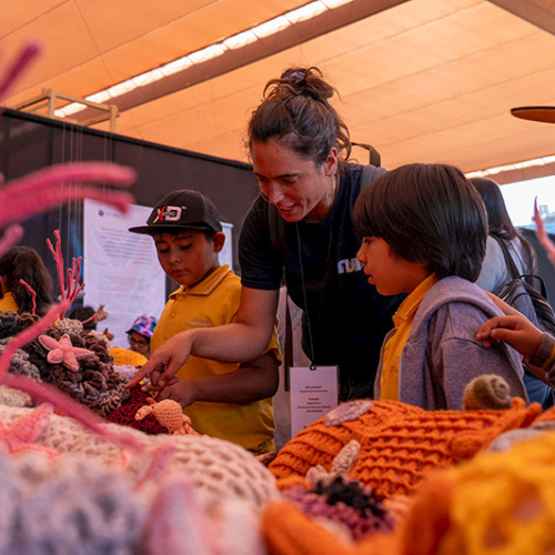 La investigadora de Núcleo NUTME, Celeste Kroeger, le muestra a unos niños la exposición